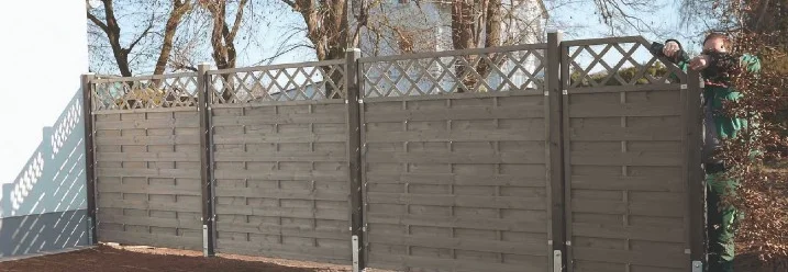 Person baut einen Gartenzaun auf